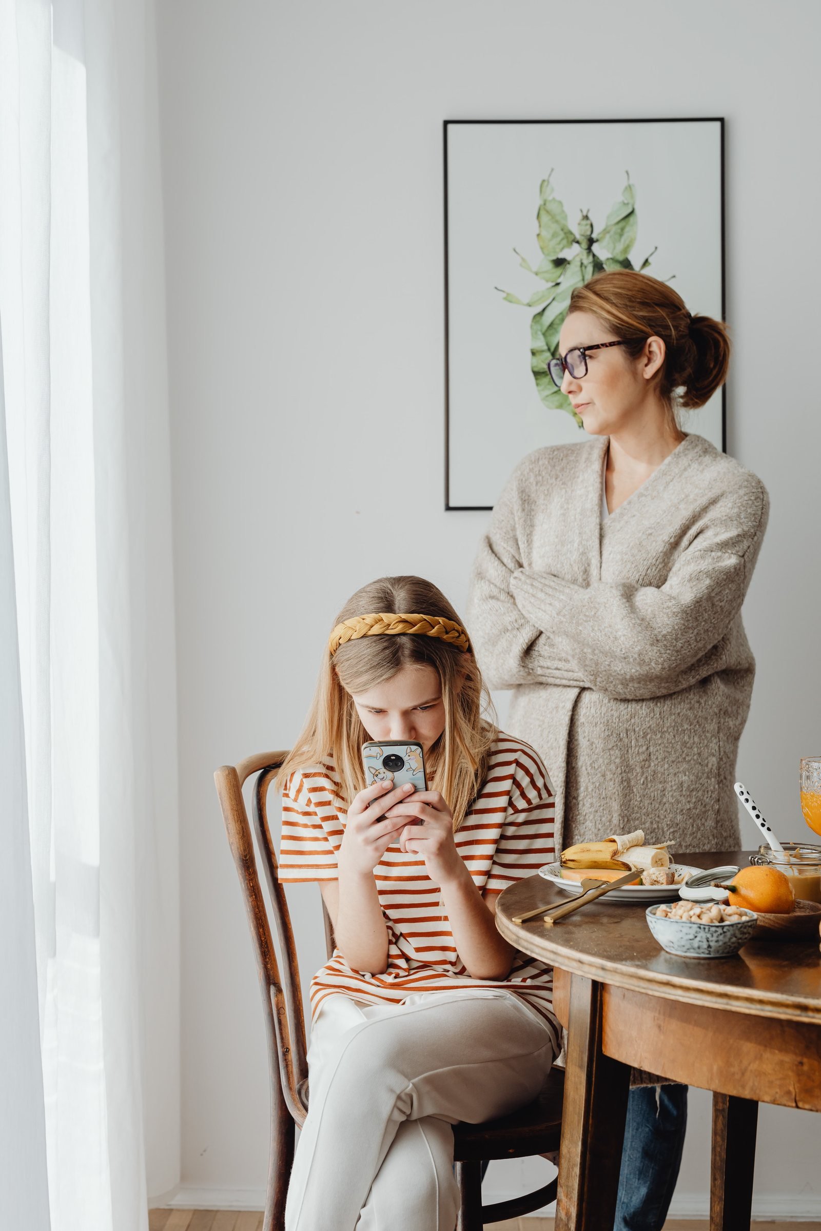 Mãe observando preocupada enquanto a filha adolescente está concentrada no celular